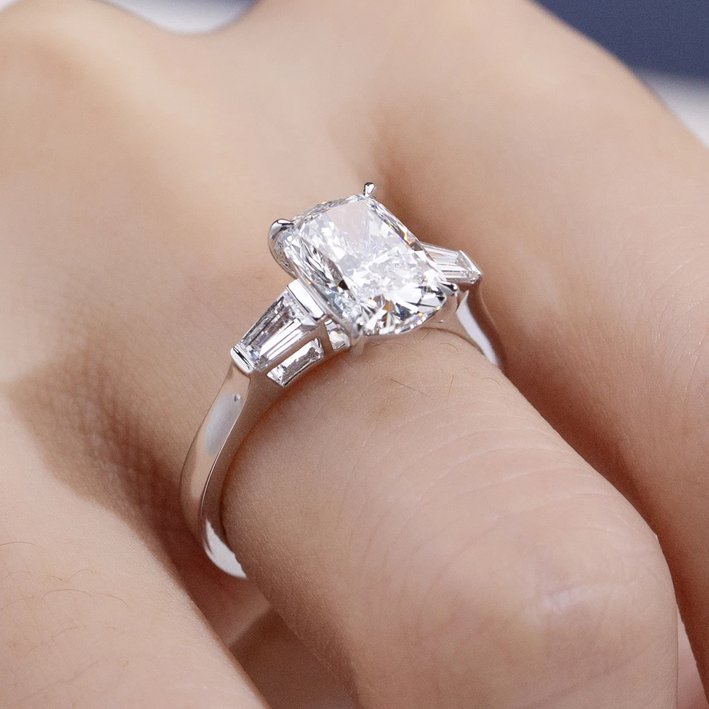 cushion cut moissanite ring, three stone engagement ring, baguette side stone ring, white gold plated ring USA, lab grown diamond alternative, luxury engagement ring for women, moissanite jewelry UK, classic bridal ring
